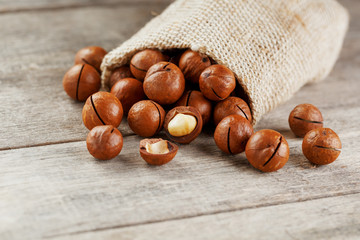 Macadamia nut on a wooden table in a bag, closeup, top view