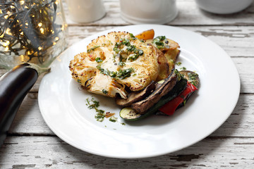 Baked cauliflower with mushrooms served with herbs.