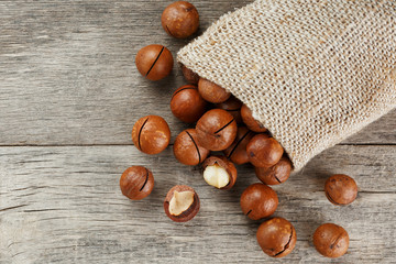 Macadamia nut on a wooden table in a bag, closeup, top view