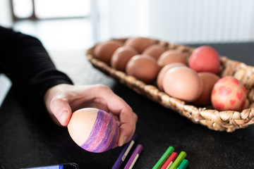 Eggs decoration, children is coloring an ester egg. Coloring eggs with pastel creativity activities for children during festivity. Craft and food