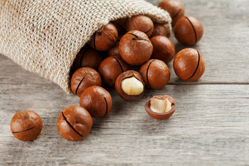 Macadamia nut on a wooden table in a bag, closeup, top view