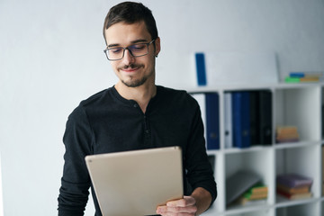 Young man working with tablet, receiving video call, talking with partners 