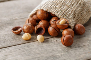 Macadamia nut on a wooden table in a bag, closeup, top view