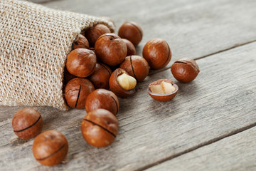 Macadamia nut on a wooden table in a bag, closeup, top view