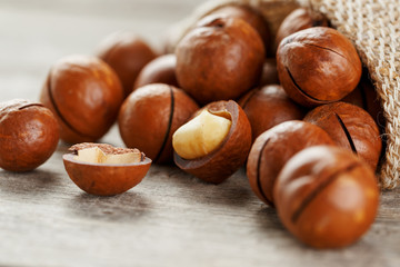 Macadamia nut on a wooden table in a bag, closeup, top view