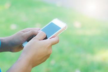 hipster woman using mobile phone touching screen at outdoor in green park background, hands typing smart phone texting messaging lifestyle working app device technology internet social online concept.