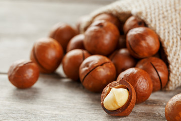Macadamia nut on a wooden table in a bag, closeup, top view