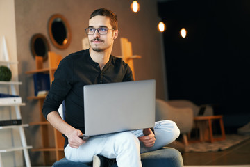 Young man sitting with computer. Freelancer in glasses working with laptop, project manager.