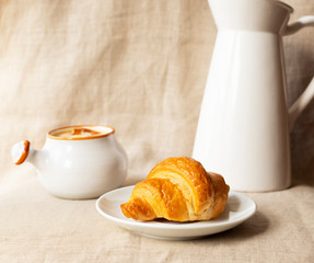 Fresh delicious croissant. Breakfast with croissant, caramel sauce and milk. Close-up. Light background