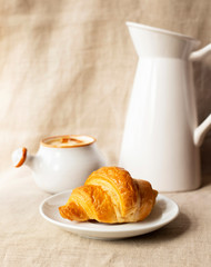 Fresh delicious croissant. Breakfast with croissant, caramel sauce and milk. Close-up. Light background