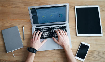 View from the top, hands working with laptop and smartphone on wooden table