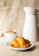 Fresh delicious croissant. Breakfast with croissant, caramel sauce and milk. Close-up. Light background