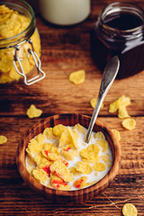 Breakfast with corn flakes, milk and berry syrup