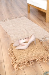 Fototapeta na wymiar beige high-heeled shoes elegant leather women's shoes on a wooden background light glossy heel shoes on a pillow of straw.