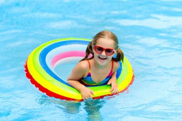 Child in swimming pool on toy ring. Kids swim.