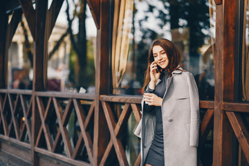 beautiful elegant girl standing in the autumn city and drinking a coffee