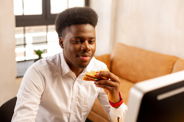 Pleasant young man holding a delicious sandwich