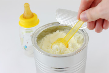 hands holding spoon of baby milk formula