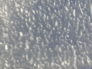 Snow crystals shine in the sun. A white blanket of snow shows the crystals that reflect the color of the sun.