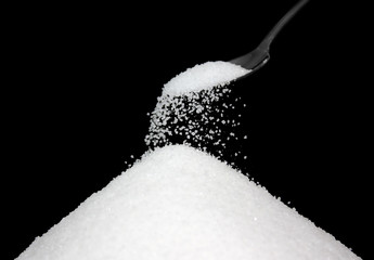 pouring white sugar from spoon