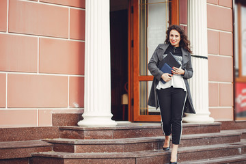 Curly girl walks. The girl is outdoors. Beautiful girl with computer