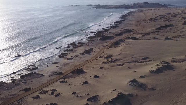Las Tortolas beach aerial footage at Atacama Desert the sunset ray lights illuminate this amazing and idyllic beach in the middle of the desert, an arid awe landscape crashed by Pacific Ocean waters
