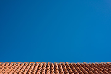 Red tile roof with blue sky as background