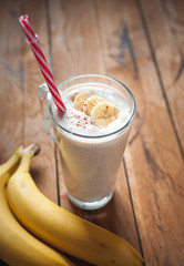 Close-up of banana and flax seeds smoothie in a glass on wooden background