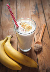 Close-up of banana and flax seeds smoothie in a glass on wooden background