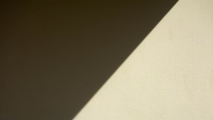 Abstract background of a pale yellow wall with shadows from the window.