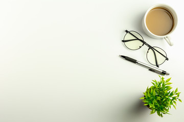 White office desk with glasses, pen and a coffee cup. - Top view with copy space.