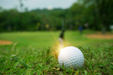 Golf ball on green grass in beautiful golf course at sunset background.