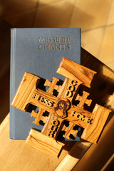 Croix de Jérusalem en bois d'olivier représentant Jésus-Christ et livre de messe et chants dans une église. / Jerusalem cross in olive wood depicting Jesus Christ and book of Mass and chants.