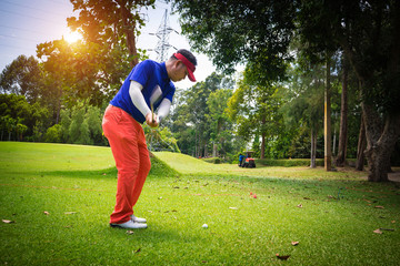 Blurred golfer playing golf on the sand in the evening golf course, on sun set evening time.