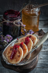 cheese pancakes with blueberries jam and flowing honey on a silver plate.