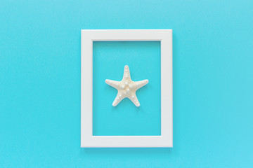 Fototapeta na wymiar White frame with starfish on blue background. Creative Flat lay Top view Template for postcard, design Copy space for text