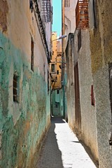 Narrow lane with walls of houses painted in different colors and in poor condition
