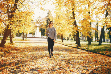 Fototapeta na wymiar pretty cute girl with make up, dressed in gray sweater standing in a autumn park 