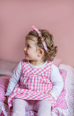 Portrait of Little Happy Girl with Curly Hair and Pink Dress.Close up of a Happy Smiling Child in a Pink Room 