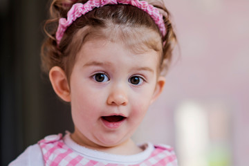 Portrait of Little Happy Girl with Curly Hair and Pink Dress.Close up of a Happy Smiling Child in a Pink Room 