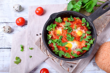 Shakshuka with tomato sauce and quail eggs topped with cilantro in a cast iron pan. Jewish cuisine meal