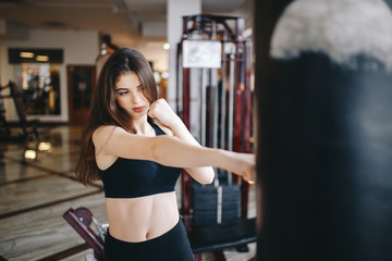 Fototapeta premium Beautiful girl in the gym. A woman performs exercises. The girl is boxing
