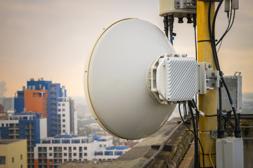 Wireless telephone transmitter is a close up. Outdoor mobile antenna is on the roof. The base station repeater is installed at the top of the building