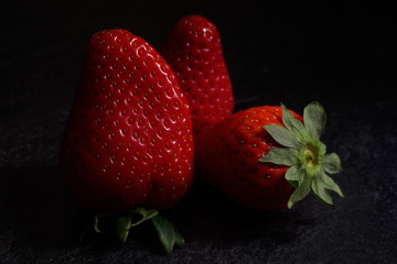 Strawberries on black textured background, dark food