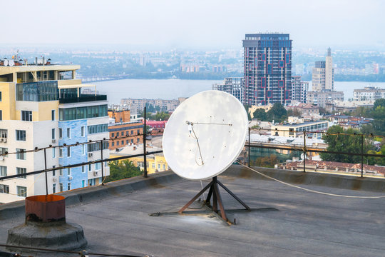 Direct-focus satellite dish is on the roof of a high building. Equipment for watching television channels. TV antenna installed in a residential quarter of the city