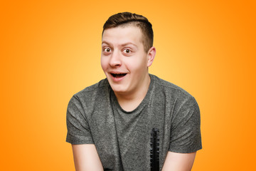 Portrait of a surprised, funny positive guy on a bright orange background in the studio.