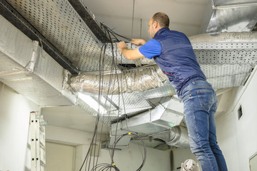 The technician is laying the fiber optic Internet cable on the technical floor. A man works with...