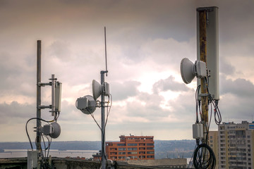 Powerful mobile base station antennas are in the background of gray clouds. There are several masts...