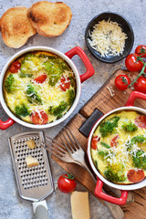 Casserole with broccoli, tomatoes and parmesan on a concrete background. View from above.