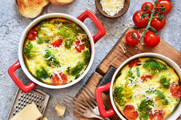 Casserole with broccoli, tomatoes and parmesan on a concrete background. View from above.